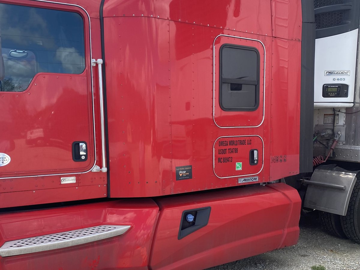 Red Kenworth truck 14588 lettered Omega World Trade LLC, USDOT 1734788, MC 889473, hooked to a reefer trailer